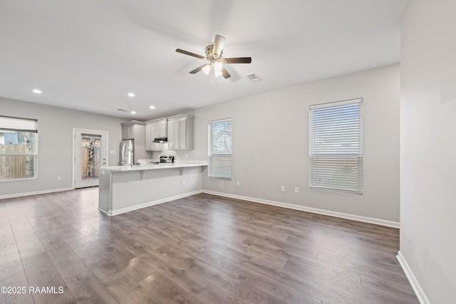 unfurnished living room with ceiling fan and dark hardwood / wood-style flooring