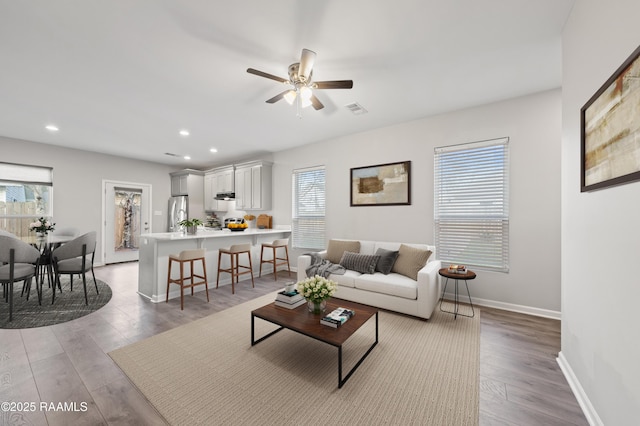 living room with light hardwood / wood-style flooring and ceiling fan