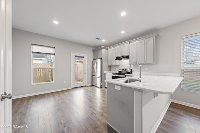 kitchen featuring kitchen peninsula, gray cabinetry, stainless steel appliances, sink, and a breakfast bar area