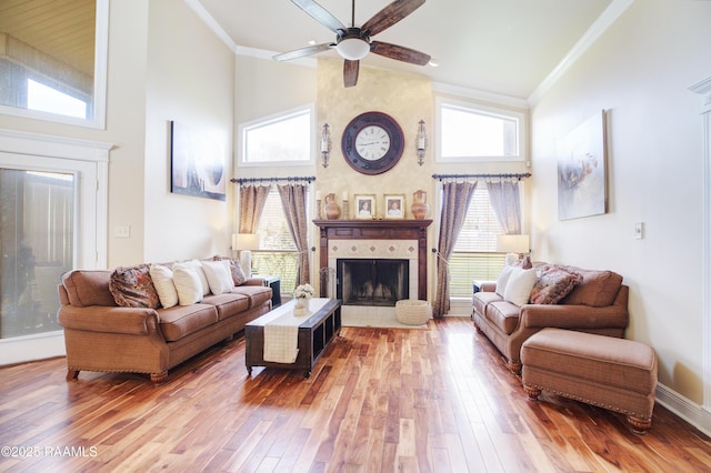 living room featuring a fireplace, crown molding, wood-type flooring, and a wealth of natural light