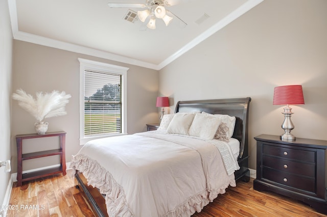 bedroom with hardwood / wood-style flooring, ornamental molding, and vaulted ceiling