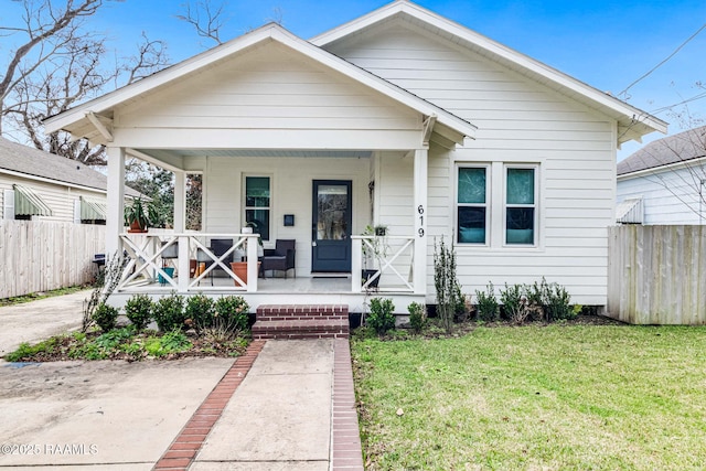 bungalow featuring covered porch and a front yard