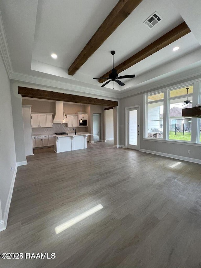 unfurnished living room with sink, beamed ceiling, dark hardwood / wood-style floors, and ceiling fan