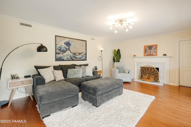 living room with a fireplace, visible vents, a chandelier, and wood finished floors