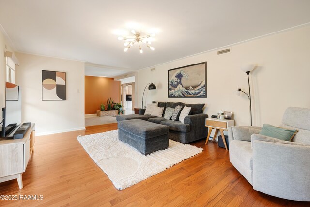 living area with a chandelier, wood finished floors, visible vents, and baseboards