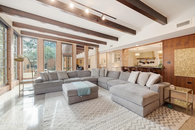 living room featuring wooden walls, visible vents, light speckled floor, and beamed ceiling