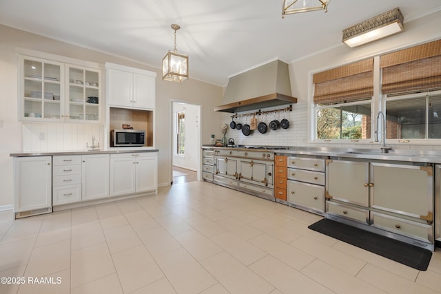 kitchen with glass insert cabinets, white cabinets, decorative light fixtures, and exhaust hood