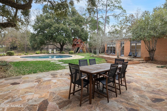 view of patio / terrace featuring a fenced in pool, fence, a playground, and outdoor dining space