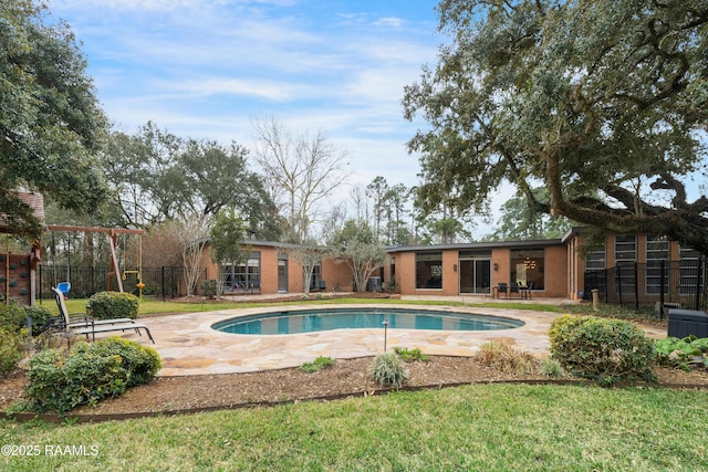 view of swimming pool featuring fence, a lawn, and a patio