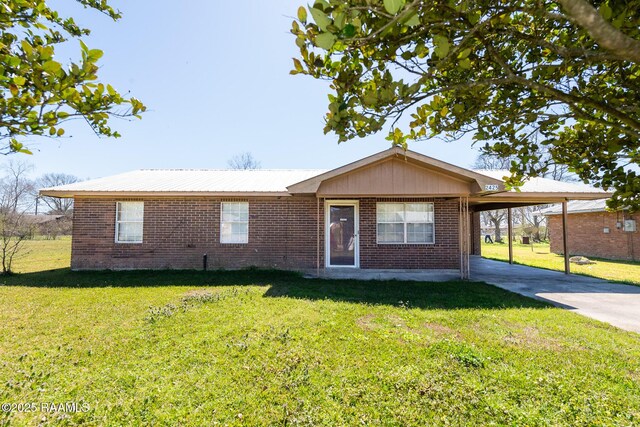 single story home featuring metal roof, brick siding, driveway, a carport, and a front yard