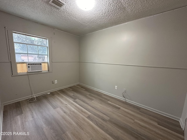 spare room featuring hardwood / wood-style flooring, a textured ceiling, and cooling unit