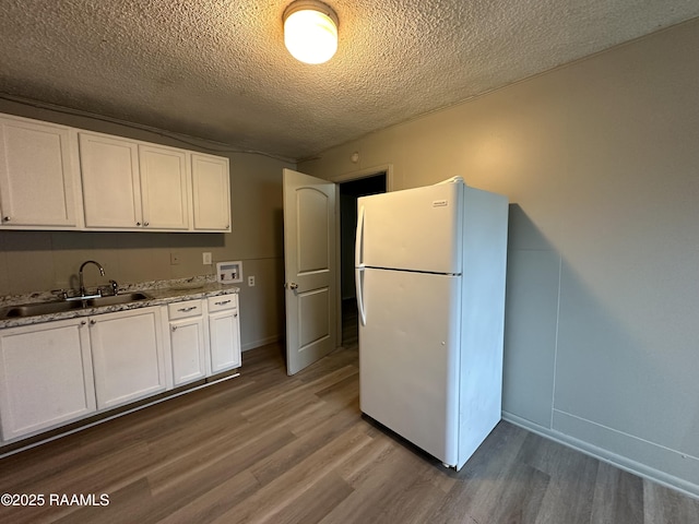 kitchen featuring sink, hardwood / wood-style floors, white cabinets, and white fridge