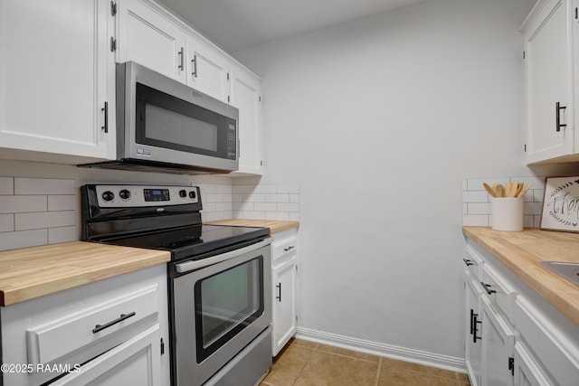 kitchen with appliances with stainless steel finishes, white cabinetry, backsplash, and light tile patterned floors