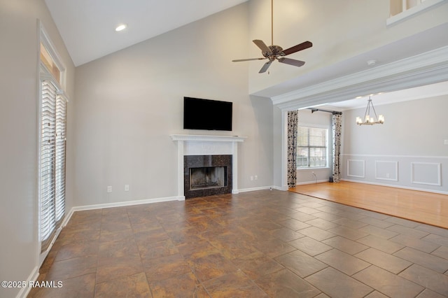 unfurnished living room with ceiling fan with notable chandelier, high vaulted ceiling, and a premium fireplace