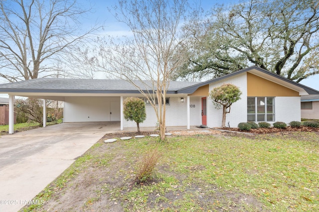 mid-century modern home with a carport, brick siding, driveway, and a front lawn