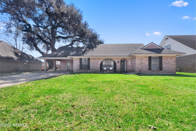 single story home featuring brick siding, roof with shingles, a front yard, a carport, and driveway