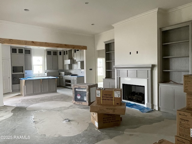 unfurnished living room with concrete floors, a fireplace, built in features, ornamental molding, and a wealth of natural light