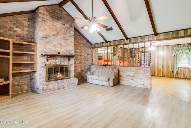 unfurnished living room with ceiling fan, high vaulted ceiling, hardwood / wood-style floors, beamed ceiling, and a brick fireplace