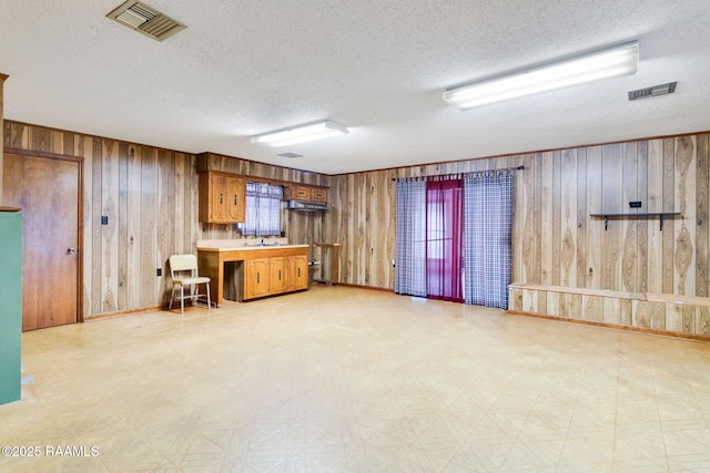 kitchen with a textured ceiling, sink, and wooden walls