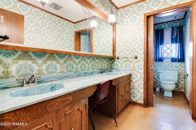 bathroom with toilet, vanity, and crown molding