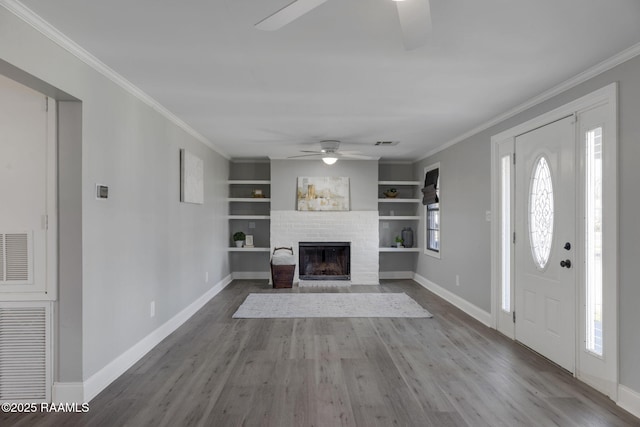 entryway featuring a brick fireplace, wood finished floors, and crown molding