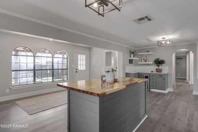 kitchen with arched walkways, open shelves, gray cabinets, visible vents, and wood counters