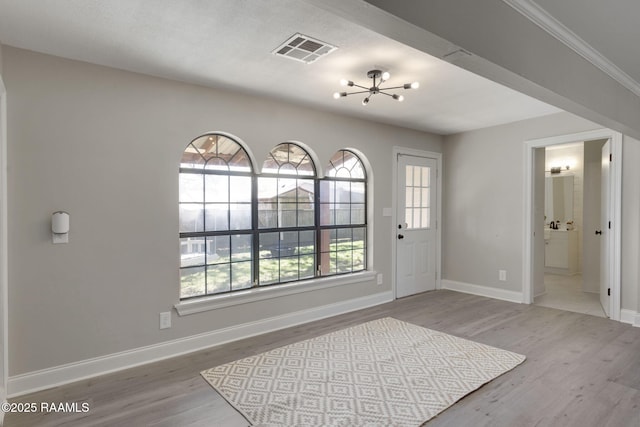 foyer entrance featuring a chandelier, wood finished floors, visible vents, and baseboards