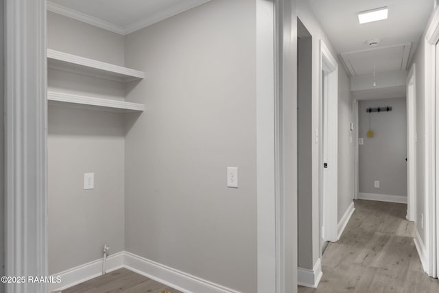 laundry area with ornamental molding, light wood finished floors, attic access, and baseboards