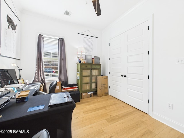 office space with a ceiling fan, visible vents, baseboards, crown molding, and light wood-type flooring