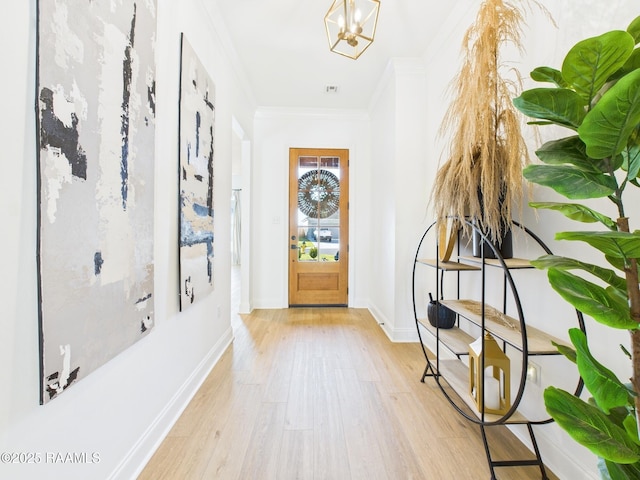 foyer featuring a chandelier, wood finished floors, baseboards, and ornamental molding