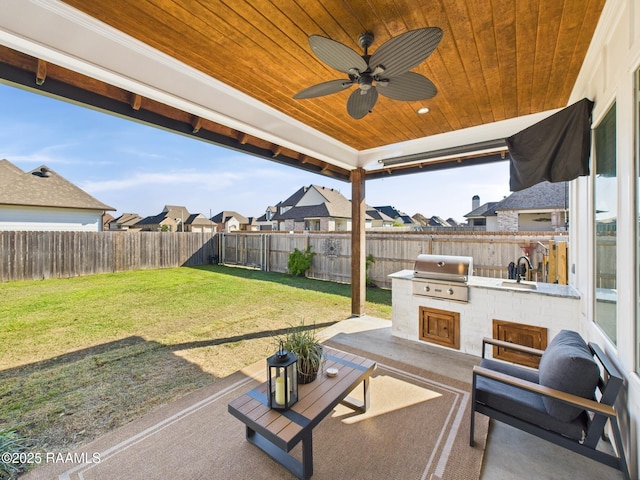 view of patio featuring a sink, a fenced backyard, a grill, and an outdoor kitchen