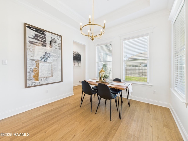 dining space featuring light wood-type flooring, a notable chandelier, a tray ceiling, crown molding, and baseboards