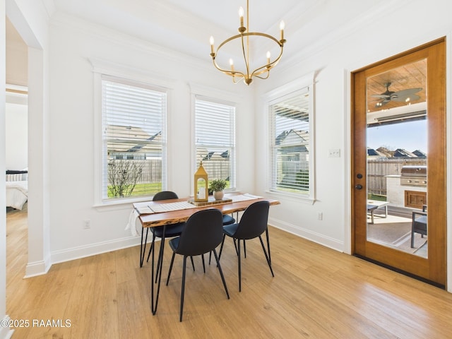 dining area featuring baseboards, a notable chandelier, crown molding, and light wood finished floors