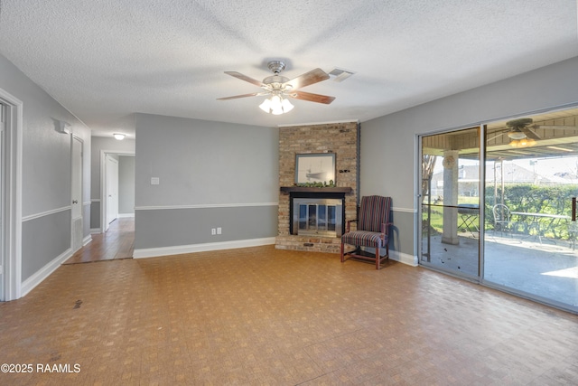 unfurnished room featuring a textured ceiling, a brick fireplace, and ceiling fan