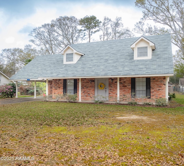 cape cod-style house with a front lawn, driveway, an attached carport, a porch, and brick siding