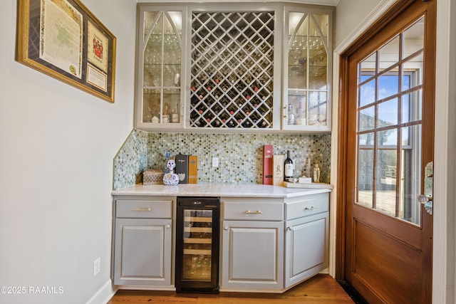 bar featuring a dry bar, beverage cooler, tasteful backsplash, and light wood-style flooring