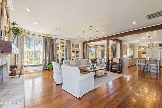 living room with light wood-type flooring, an inviting chandelier, a fireplace, and visible vents