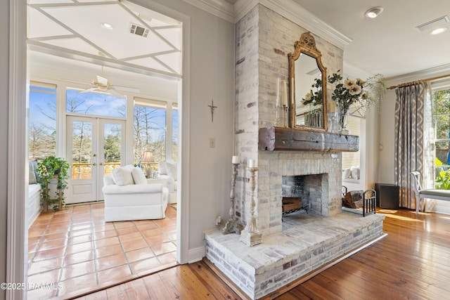 unfurnished room featuring visible vents, wood finished floors, crown molding, french doors, and a fireplace