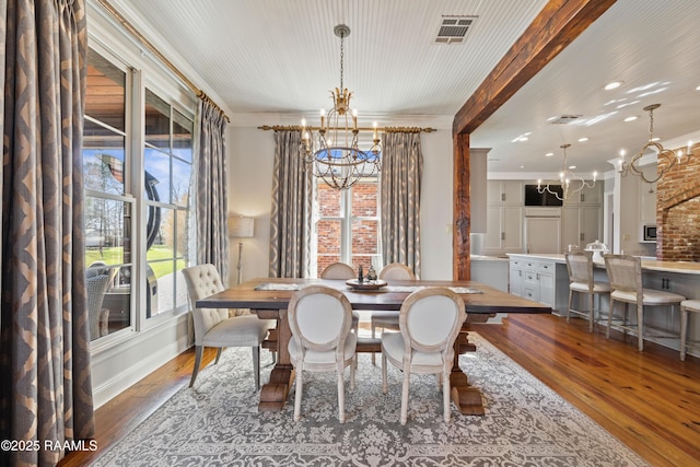 dining room with crown molding, visible vents, dark wood-style flooring, and a notable chandelier