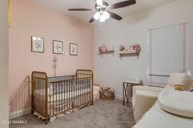 carpeted bedroom with ceiling fan, a crib, and baseboards