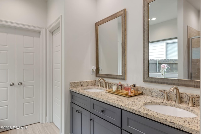 bathroom featuring a shower with shower door, a sink, and double vanity