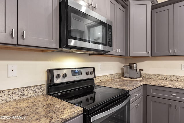 kitchen featuring appliances with stainless steel finishes, light stone counters, and gray cabinetry