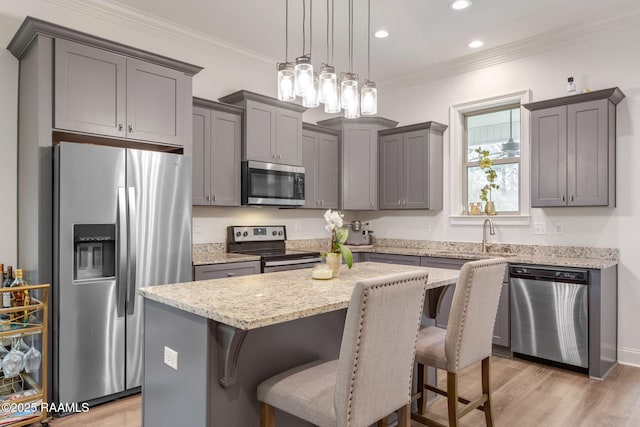 kitchen with ornamental molding, a breakfast bar, a center island, stainless steel appliances, and pendant lighting