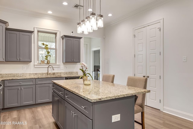 kitchen featuring gray cabinetry, a breakfast bar area, a sink, and a center island