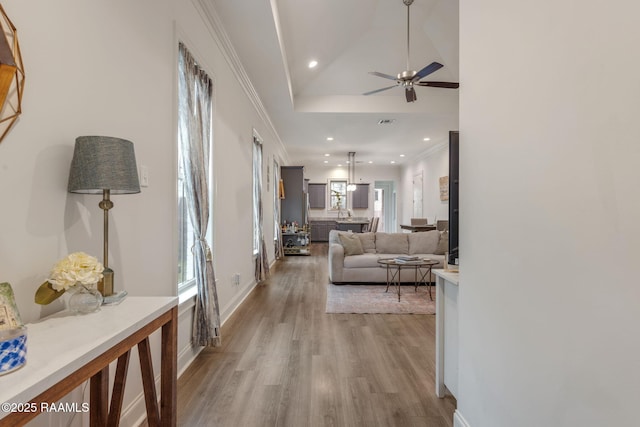 corridor with recessed lighting, ornamental molding, light wood-style floors, high vaulted ceiling, and baseboards