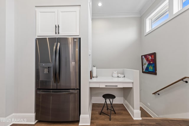 kitchen with baseboards, white cabinets, stainless steel fridge with ice dispenser, wood finished floors, and built in desk