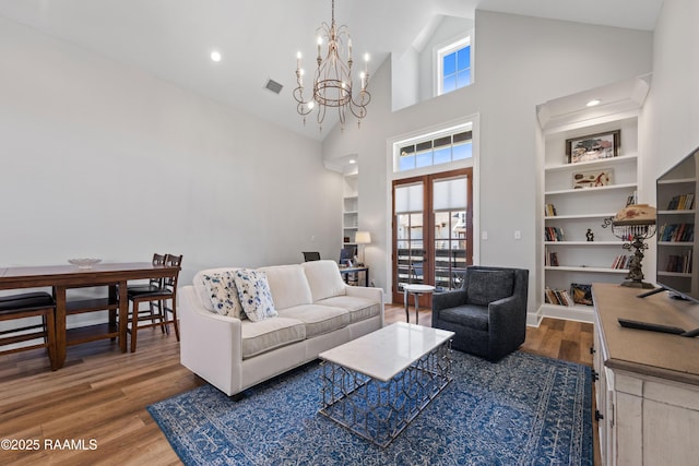 living area featuring built in features, french doors, a healthy amount of sunlight, and wood finished floors