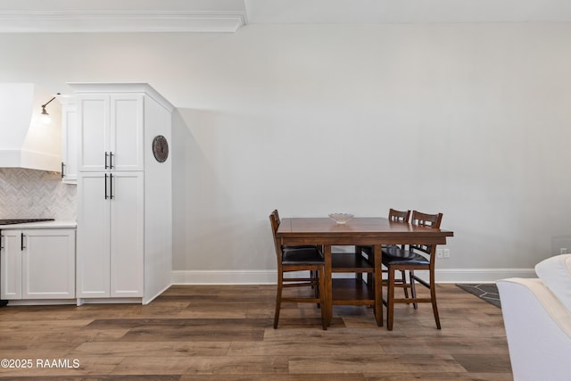 dining room with ornamental molding, dark wood-style flooring, and baseboards