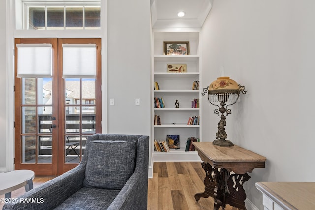 home office with light wood-style floors, french doors, baseboards, and built in shelves