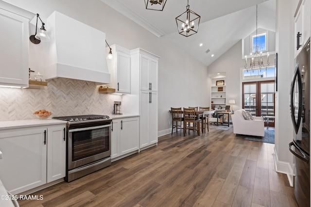 kitchen with freestanding refrigerator, stainless steel gas stove, and white cabinetry